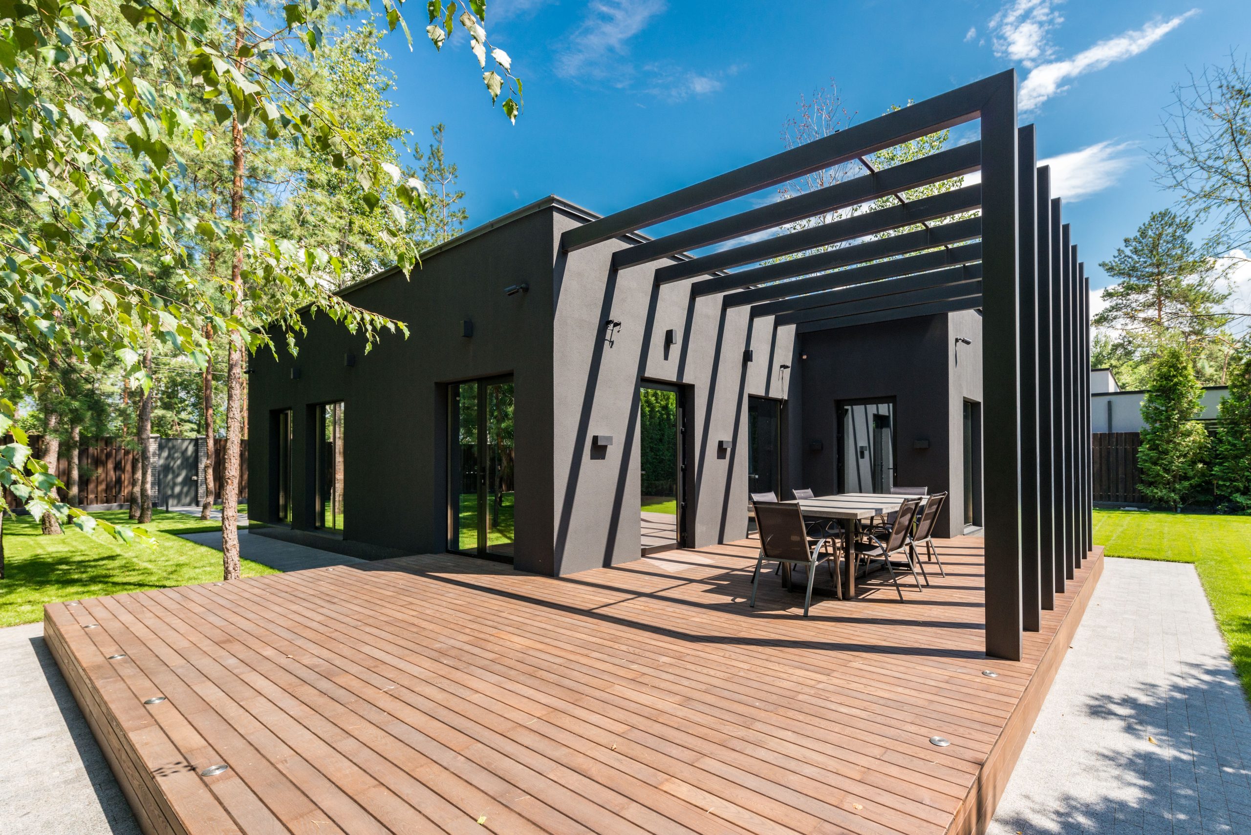 composite-deck-backyard-outdoor-living Stylish outdoor deck with dining furniture and lush greenery, illustrating the finished look and lifestyle value of composite decking.