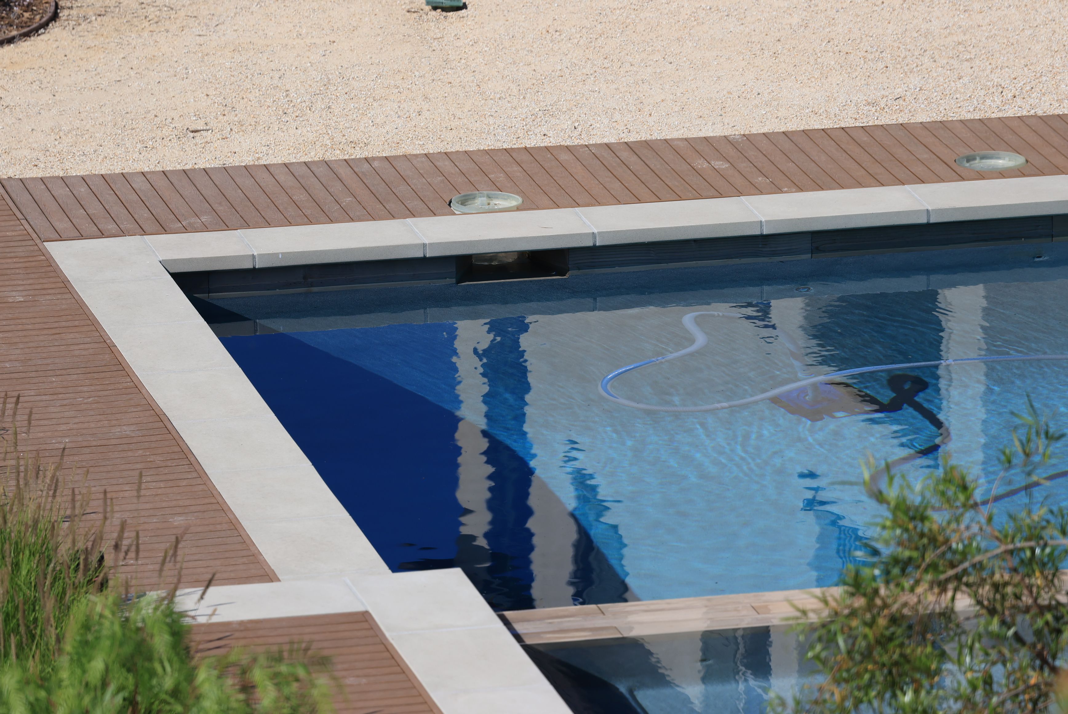 Sunny swimming pool bordered by wood decking, illustrating outdoor durability and long-term deck enjoyment.