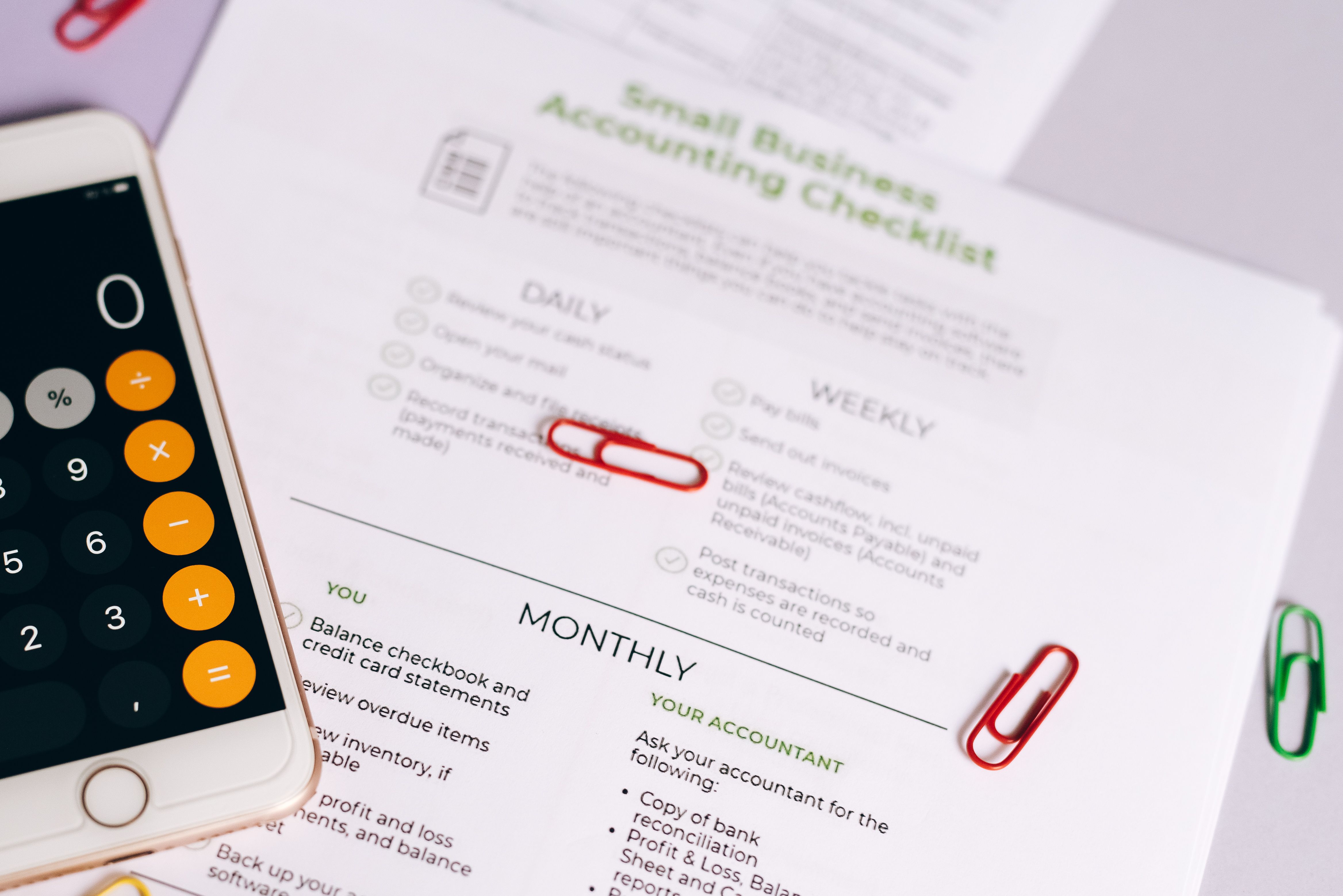 A checklist and calculator on a desk representing measurable responsibilities, oversight, and organizational controls.